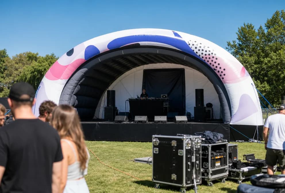 Giant inflatable stage tent operating outdoors in daytime with event equipment nearby