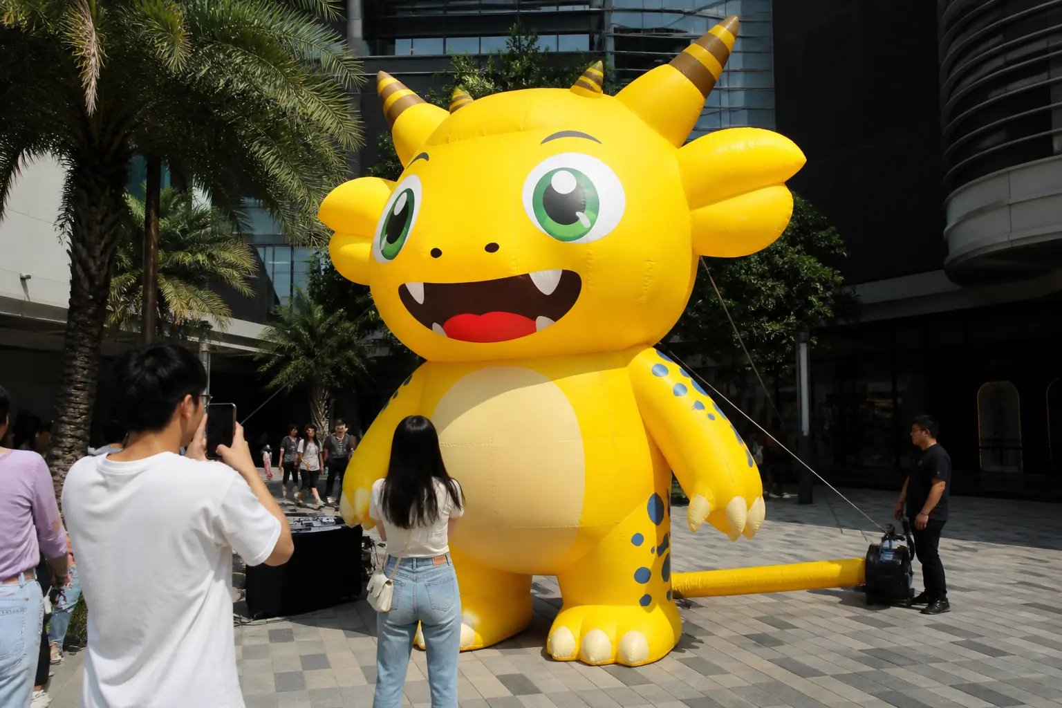 Original yellow custom inflatable cartoon mascot installed outdoors for a brand activation event